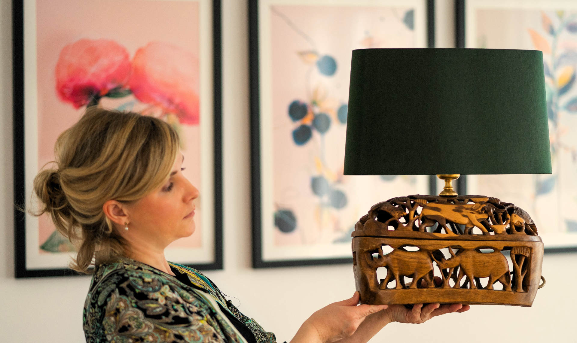 Irina präsentiert eine handgefertigte AMANEL Lampe mit geschnitztem Holzfuß und grünem Schirm